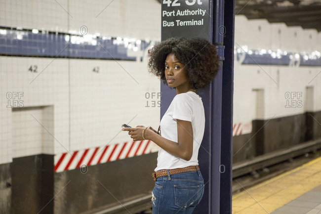 Young woman leaning against a steel column at a subway terminal
