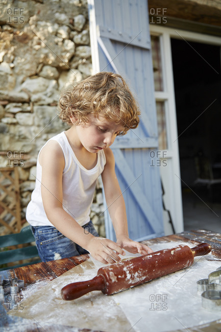 Little boy standing at an outdoor table making cookies