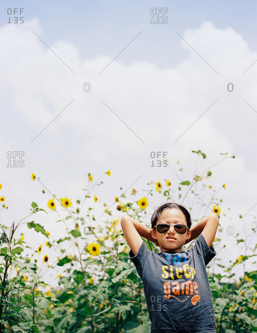 Boy with aviator sunglasses standing in a field of yellow flowers