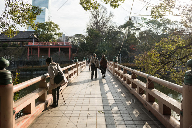 People crossing a pedestrian bridge at a park in Osaka, Japan