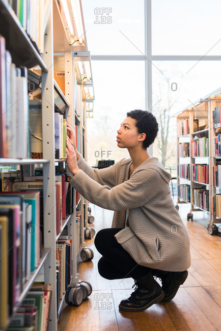 Young woman browsing for books on a shelf in a library