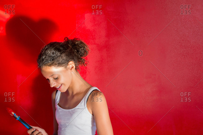 Girl painting wall red with paintbrush