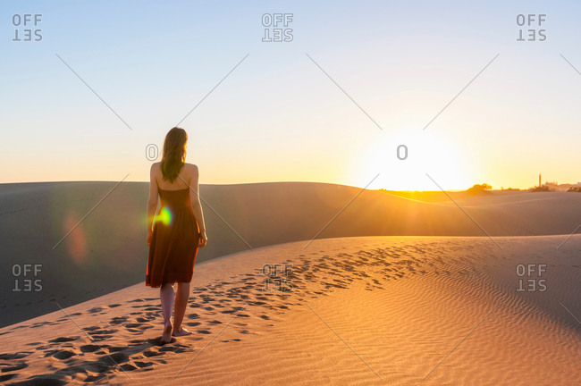 Rear view of woman strolling on dune at sunset, Maspalomas, Gran Canaria, Canary Islands, Spain
