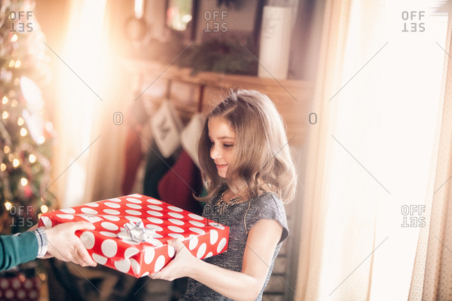 Side view of girl receiving gift at Christmas looking down smiling