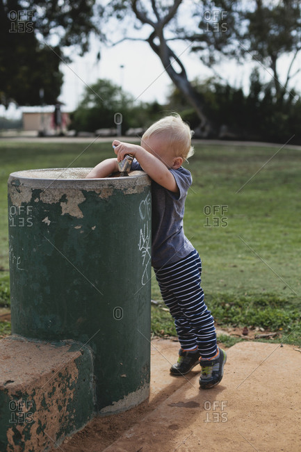Little boy reaching into an outdoor drinking fountain