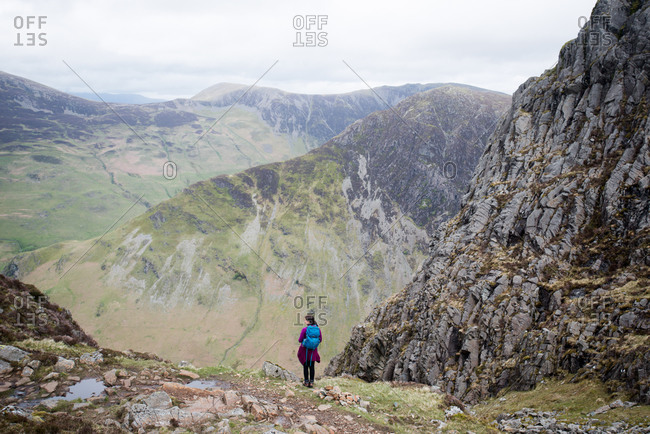 A hiker in the Lake District in England standing near the top of Haystacks above Butteremere