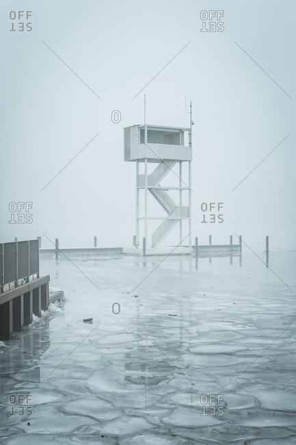 View to frozen Mueggelsee lake in Germany with diving tower in the fog