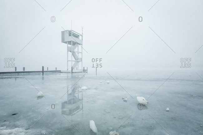 View to frozen Mueggelsee lake with diving tower in the fog