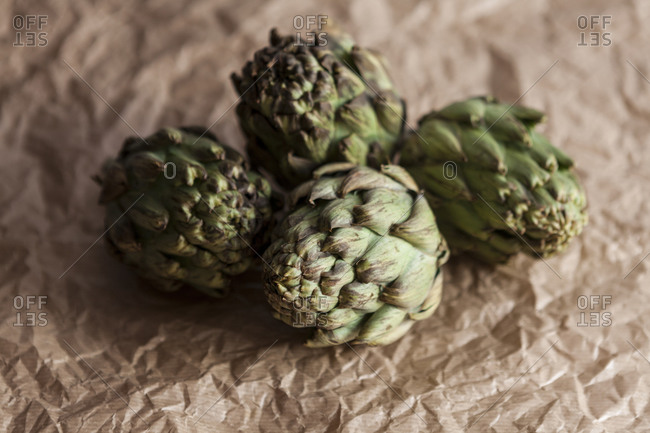 Four artichokes on crumpled brown paper