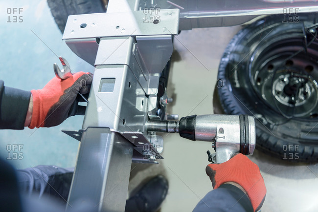 Gloved hands using spanner and ratchet on automotive production line