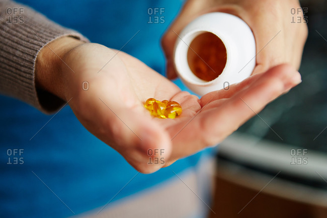 Young woman taking medication from bottle, close-up
