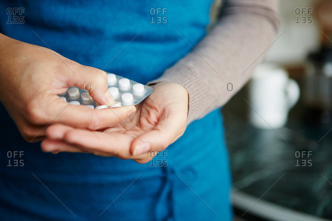 Young woman taking medication from blister pack, close-up