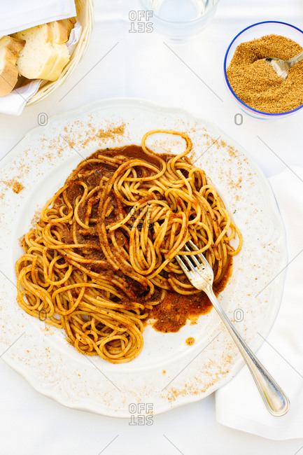 Plate of spaghetti with roasted tomatoes and spicy red pepper on restaurant table, Sicily, Italy