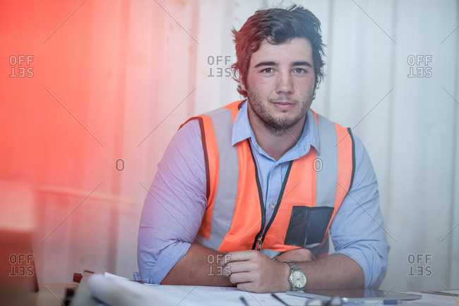 Portrait of young male construction worker  sitting at desk in portable cabin