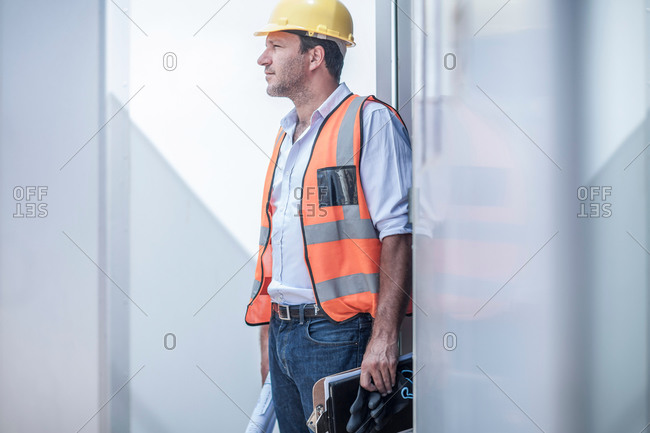 Construction foreman looking out from doorway of portable cabin on construction site