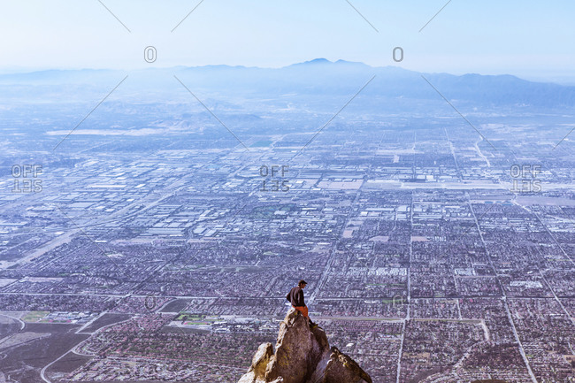 Young man sitting on mountain top, Mount Baldy, California, USA