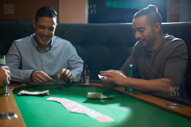 Men placing cash for card game at pub card table