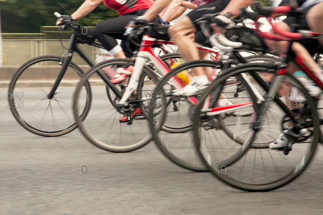 Waist down view of group of racing cyclists speeding on urban road in racing cycle race