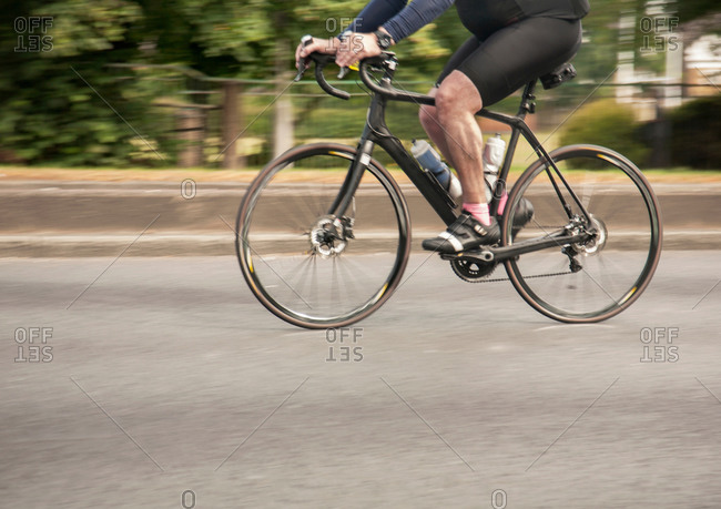 Waist down view of racing cyclist speeding on urban road in racing cycle race