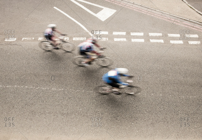 Overhead view of three cyclists speeding on urban road in racing cycle race
