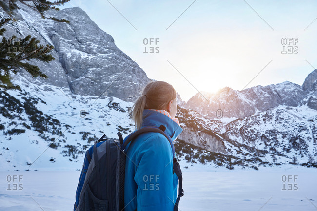Young woman hiking in snow and watching the sun on mountain top, Austria