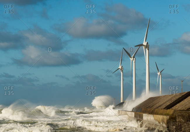 Stormy ocean waves splashing wind turbines on harbor wall, Boulogne-Sur-Mer, Pas de Calais, France