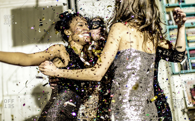 Friends dancing together in confetti at a party
