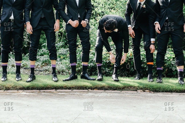 Groomsmen standing side-by-side with pant legs pulled up to display colored dress socks