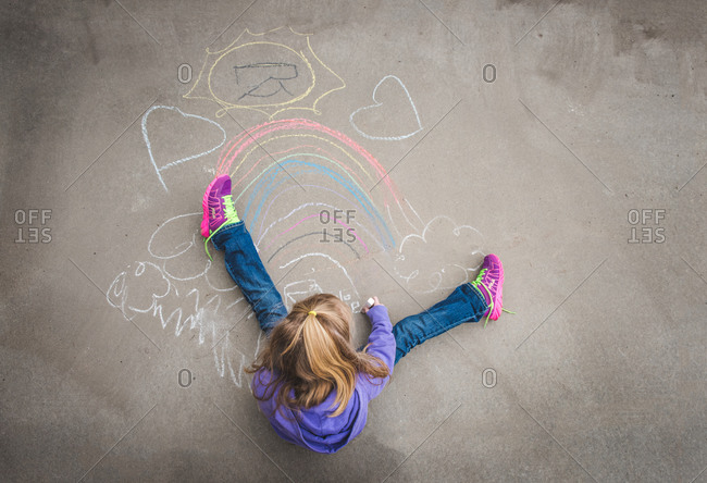 Overhead view of young girl drawing with chalk on pavement