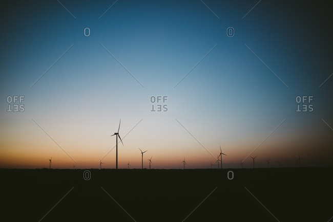 Silhouette of wind turbines at sundown