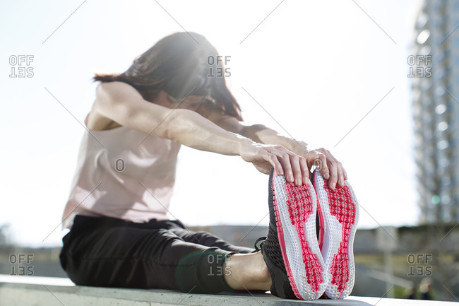 Woman wearing running shoes touching her toes while stretching to prepare to go for a run