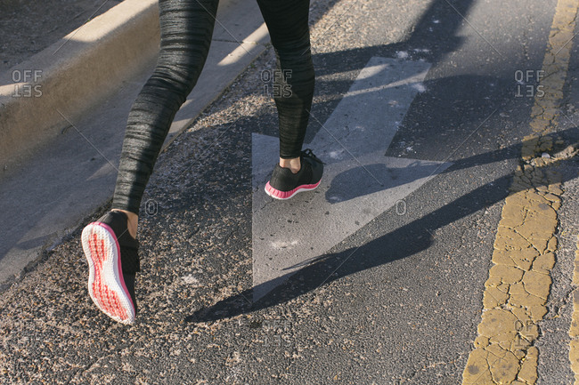 Close-up of woman\'s shoes as she is running on the street