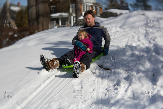Father sledding with his toddler daughter