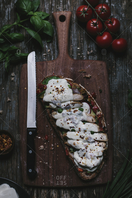 An open-face chicken caprese sandwich covered with melted mozzarella cheese