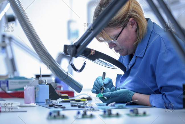 Female worker assembling electronics in electronics factory
