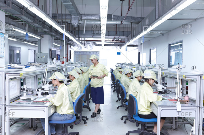Manager overseeing quality check station in factory producing flexible electronic circuit boards