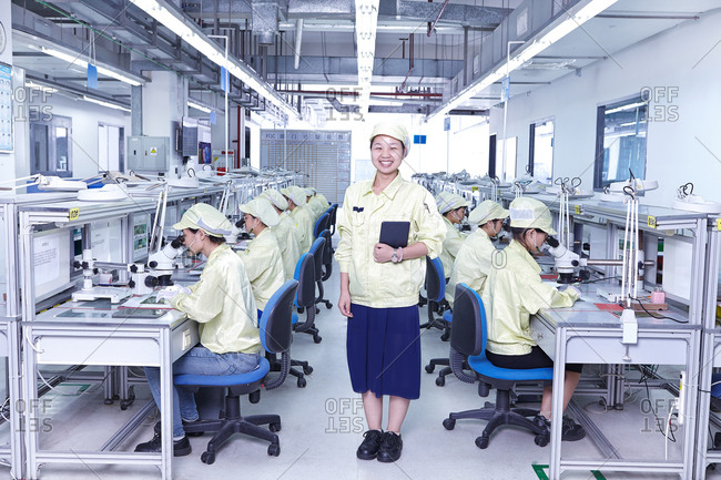 Manager overseeing quality check station at factory making flexible electronic circuit boards