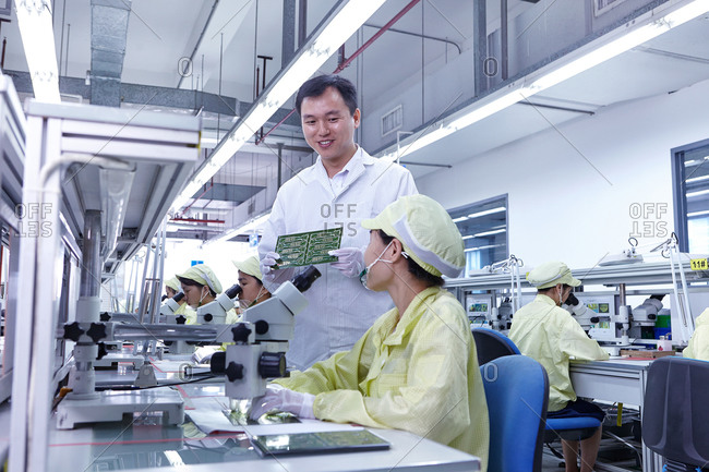 Supervisor overseeing quality check station at factory making flexible electronic circuit boards
