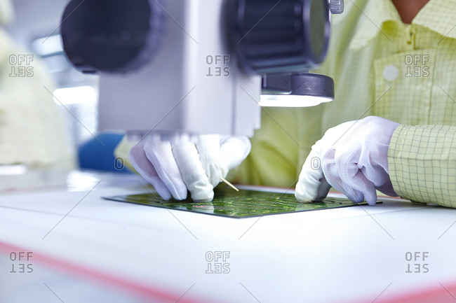 Young woman producing flexible electronic circuit boards in factory