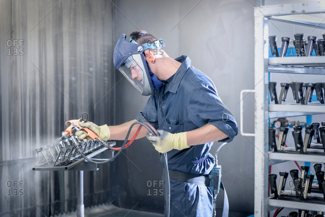 Worker paint spraying automotive parts in spray paint factory