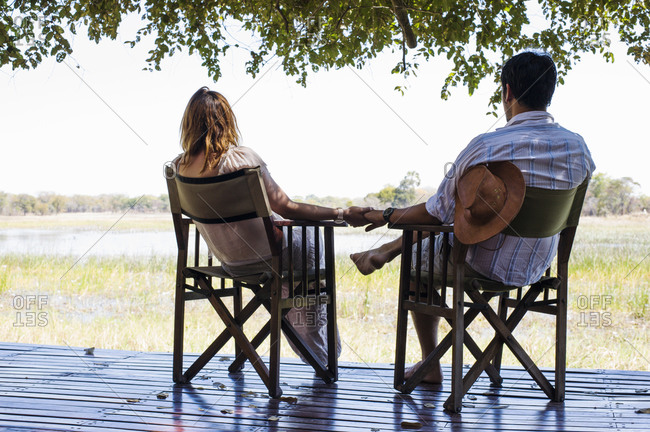 Romantic couple holding hands whilst sitting  at safari lodge, Kafue National Park, Zambia
