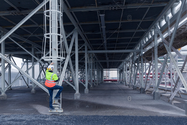 Engineer climbing ladder in warehouse space at geothermal power station