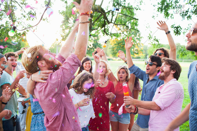 Adult crowd celebrating with arms raised at sunset party in park