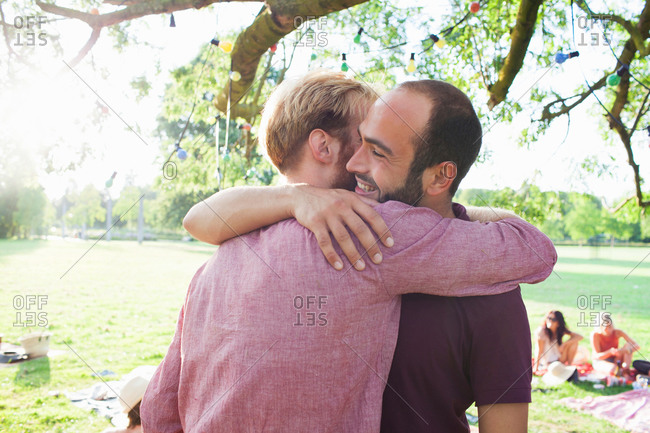 Two young men hugging each other at party in park