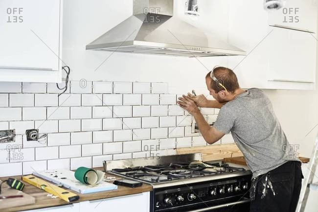 A man setting tile in a new kitchen
