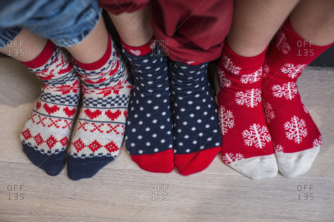 Three pairs of children\'s feet in bright patterned Christmas socks
