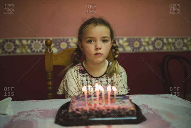 Portrait of sad little girl with birthday cake