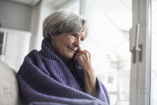 Portrait of pensive senior woman sitting on couch at home