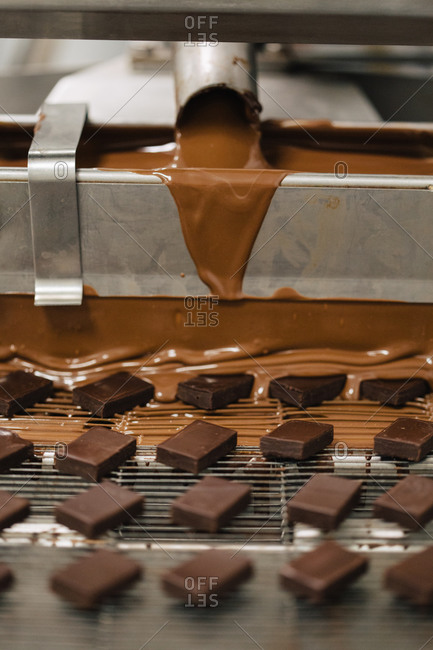Creamy chocolate flowing onto candy squares