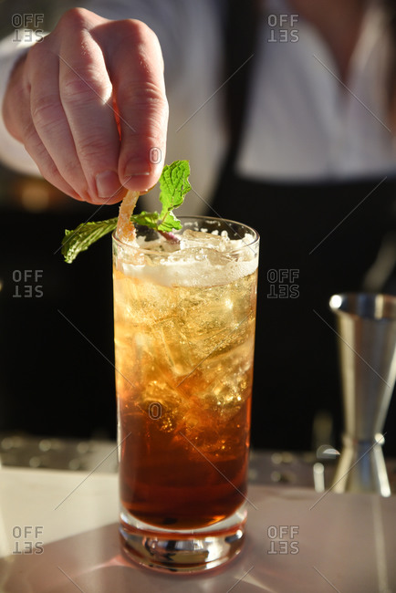 Bartender garnishing a mixed drink on a bar top